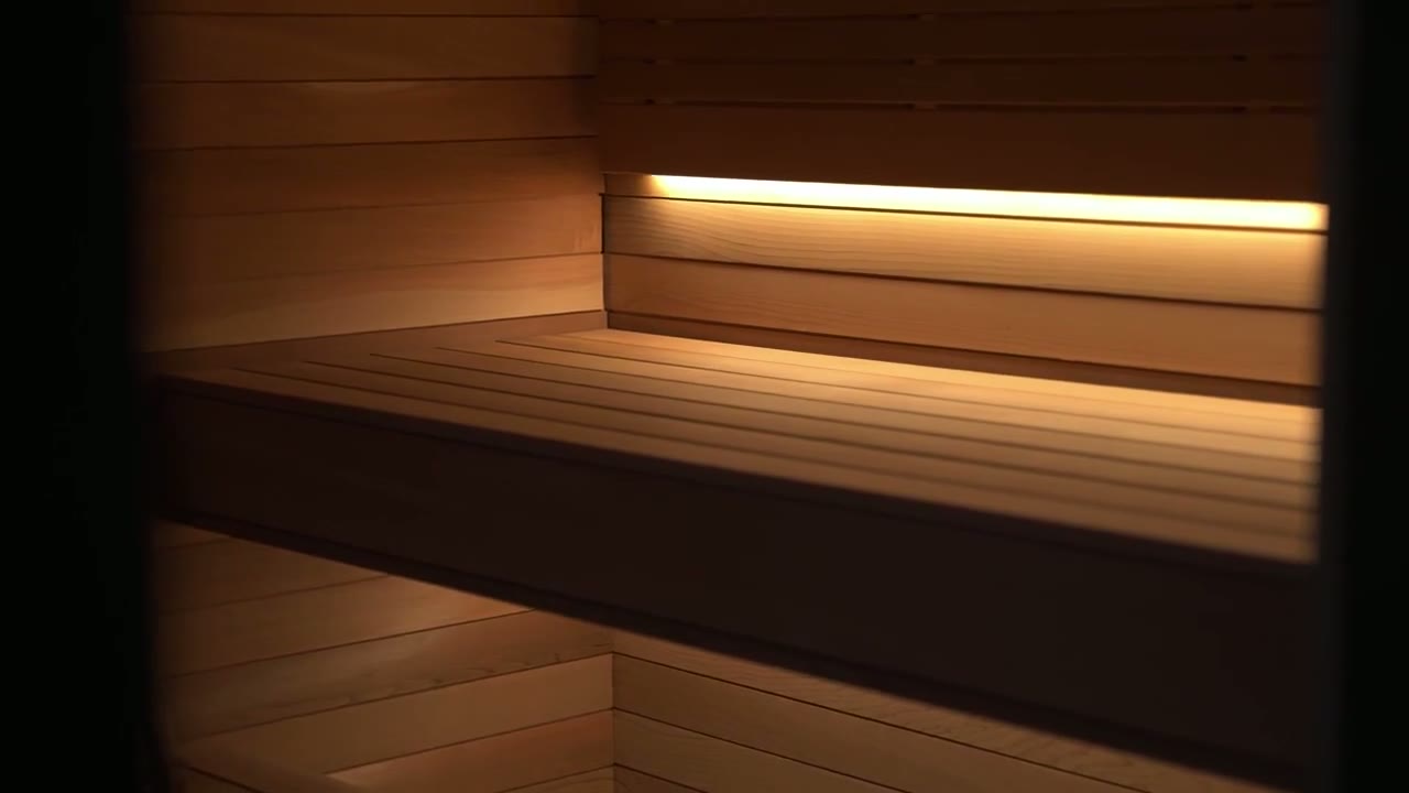 Steam rising from hot sauna stones in a warm cedar-lined sauna